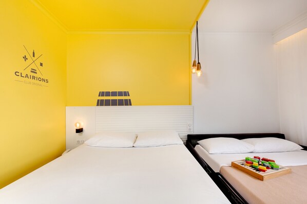 A hotel room with two beds, a yellow wall, and a logo on the left.
