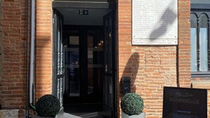 A brick building with a sign reading 'BOURDELLE' and a menu board.