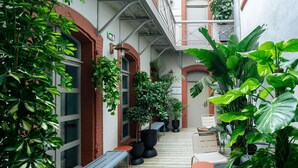 A covered outdoor area with benches, tables, and potted plants.