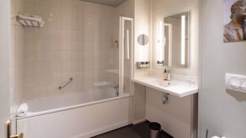 A bathroom with a bathtub, a sink, a mirror, and a toilet.