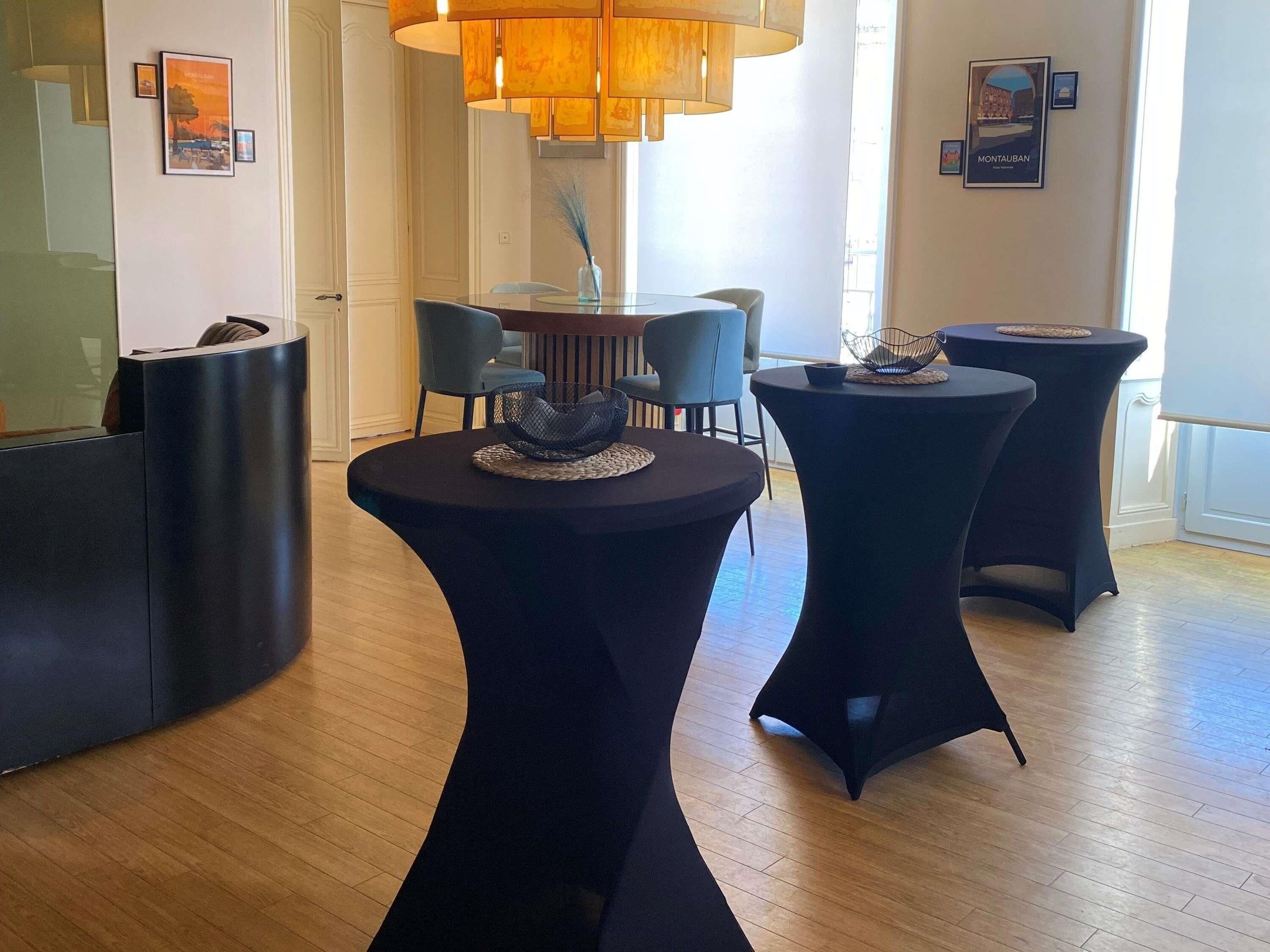 A modern interior with round tables, a large chandelier, and framed pictures on the walls.
