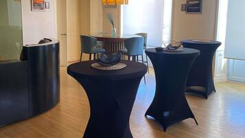 A modern interior with round tables, a large chandelier, and framed pictures on the walls.