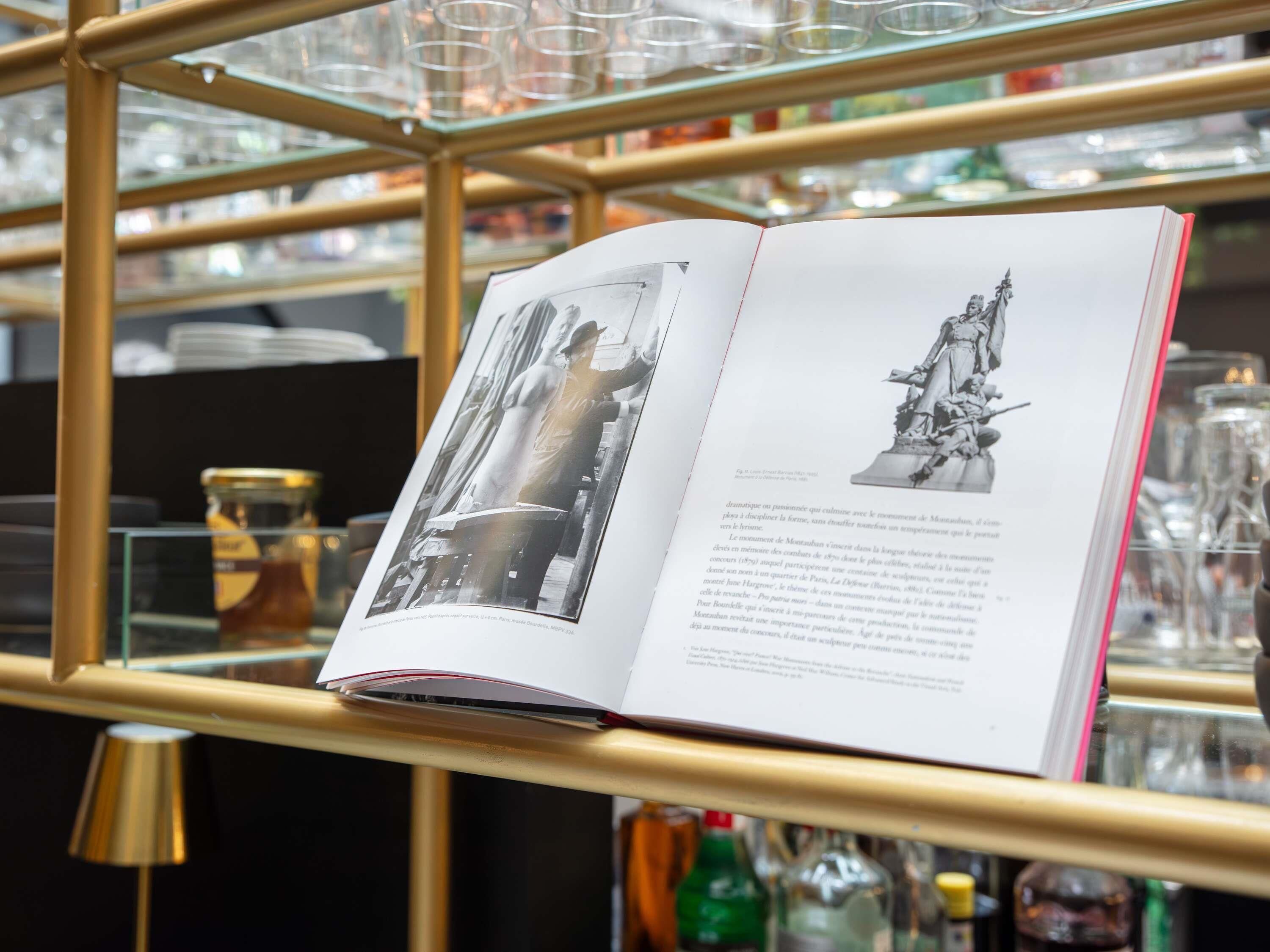 Un libro abierto con una fotografía y una estatua sobre sus páginas.