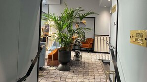 A reception area with a potted plant, a seating area with chairs, and a staircase leading to another level.