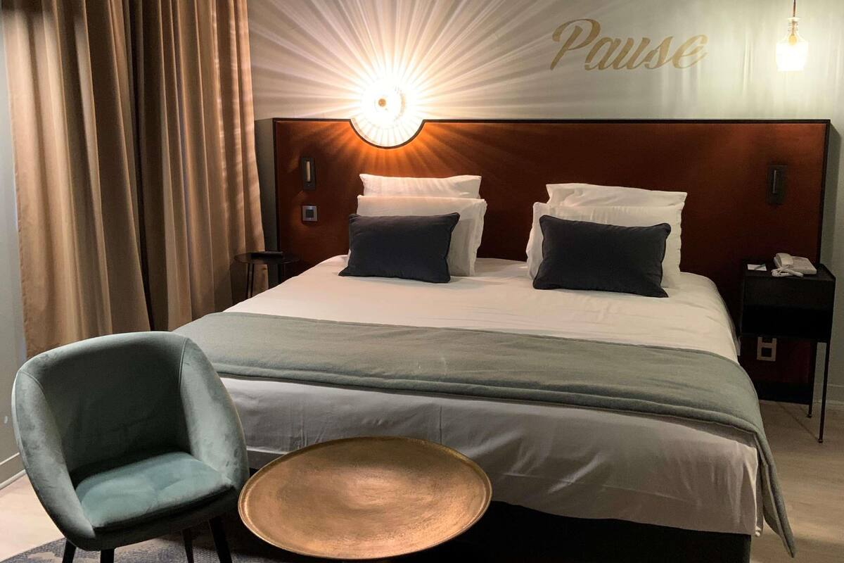 Ein Hotelzimmer mit einem Bett, einem Sessel, einem kleinen Tisch und einer Wandleuchte.