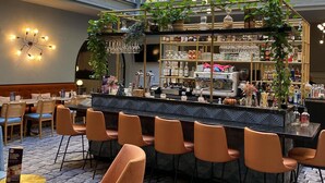 A bar area with a counter, bar stools, and shelves stocked with bottles and glasses.