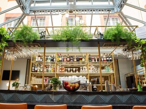 A bar area with shelves of liquor bottles and hanging wine glasses, a coffee machine, and a decorative bowl.
