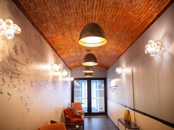 A hallway with brick ceiling, modern pendant lights, and a mural of birds on the wall.