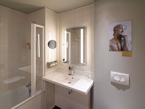 Un baño moderno con cabina de ducha de vidrio, un lavabo blanco con espejo y un aplique en la pared.