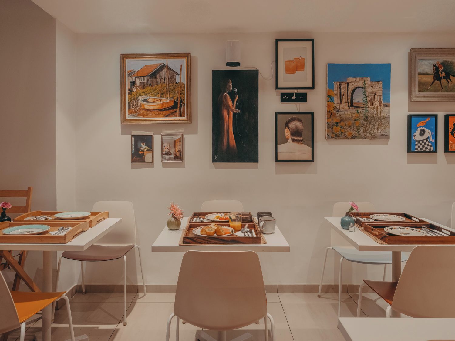 Un comedor con mesas dispuestas para dos, cada una con una bandeja de comida y cubiertos.