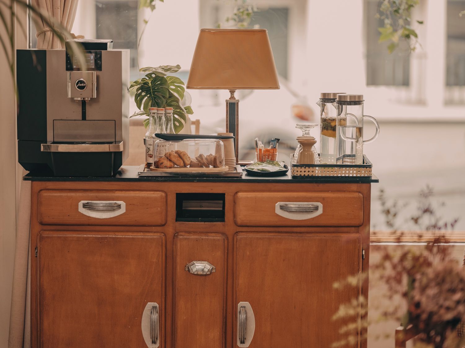 Une petite cuisine équipée d’une machine à café, d’une lampe, d’une cafetière et d’une plante.