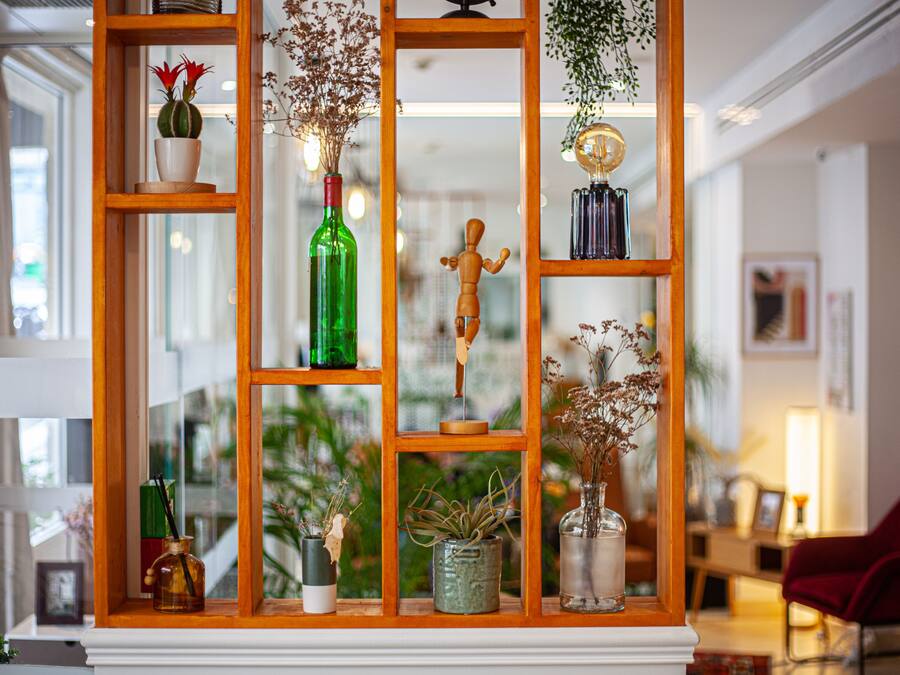 Una estantería de madera con varios objetos decorativos, como jarrones, una figura de madera y plantas.