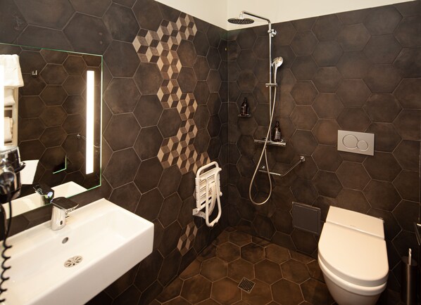 Ein Badezimmer mit einem weißen Waschbecken, einer Toilette und einer Dusche mit Duschhandstück.