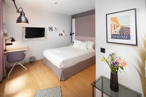 Ein modernes Schlafzimmer mit Bett, Schreibtisch, Stuhl und einem an der Wand befestigten Fernseher.