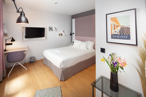 A modern bedroom with a bed, desk, chair, and a wall-mounted TV. - Hôtel Vendome Saint Germain (Paris)