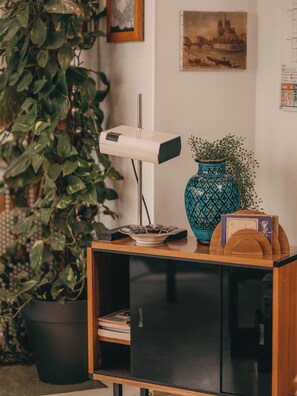 A room with a wooden cabinet, a potted plant, a vase, and a framed picture on the wall. - Hôtel Vendome Saint Germain (Paris)
