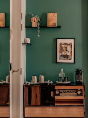 A room with a green wall, a framed picture, a shelf with books, and a vintage radio. - Hôtel Vendome Saint Germain (Paris)