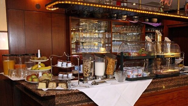 A bar area with a variety of food items, glassware, and a coffee machine. - Hotel Am Zoo (Frankfurt)