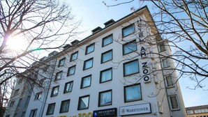 A multi-story building with signs for "HOTEL AM ZOO," "BRASSERIE AM ZOO," and "WARSTEINER." - Hotel Am Zoo (Frankfurt)