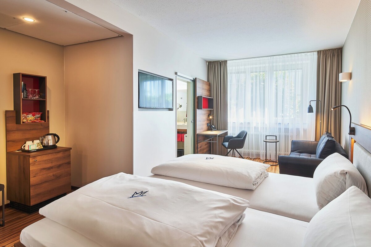 A hotel room with a bed, a desk, a chair, a wardrobe, and a bathroom.