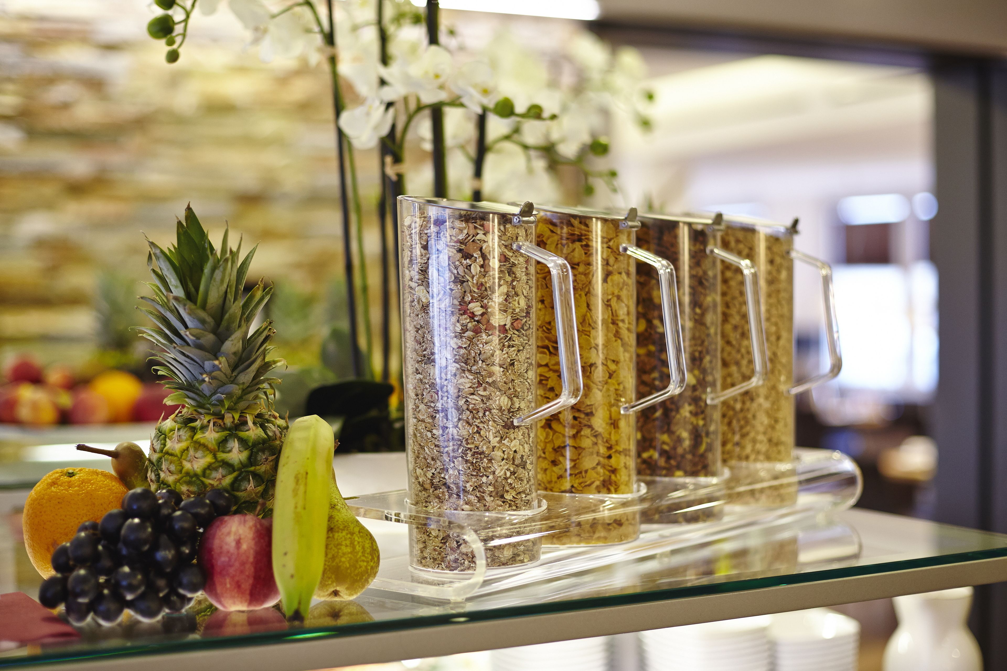 Un expositor de vidrio con varias frutas y una planta decorativa.