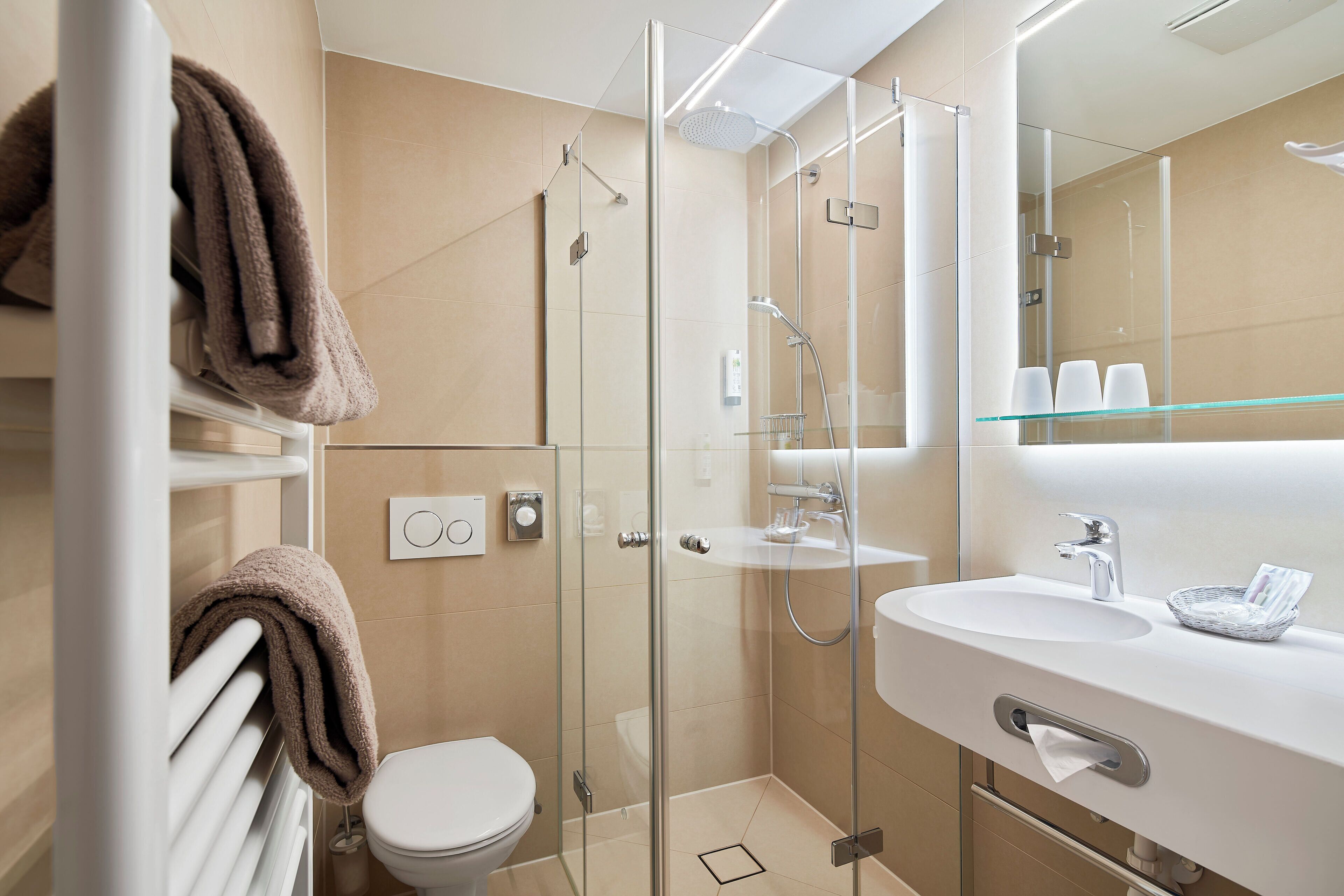 Ein modernes Badezimmer mit einer begehbaren Glasdusche, einem weißen Waschbecken und einer Toilette.