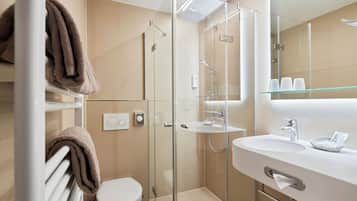 Ein modernes Badezimmer mit einer begehbaren Glasdusche, einem weißen Waschbecken und einer Toilette.