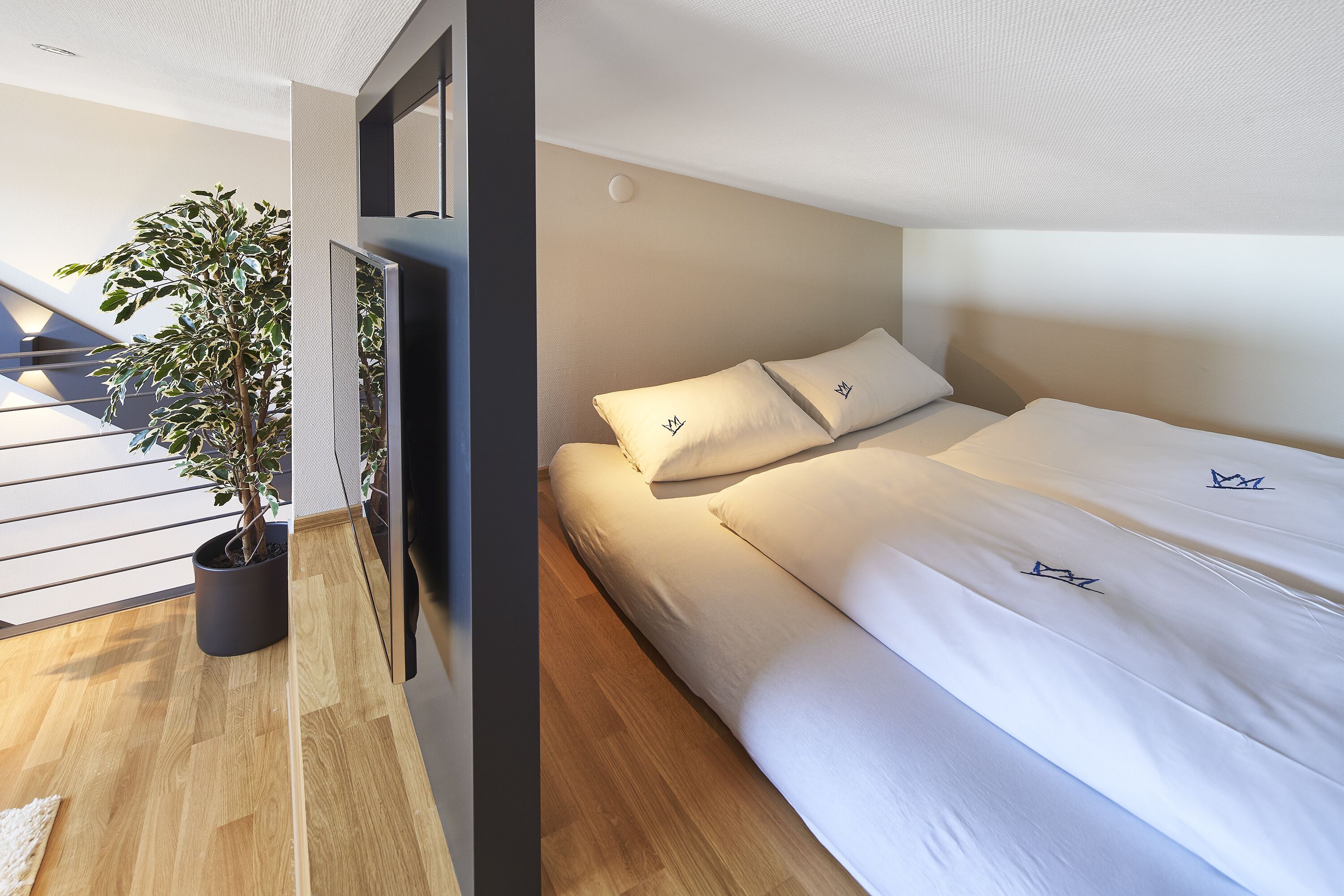 Un dormitorio moderno con una cama, una planta en maceta y vistas al exterior.