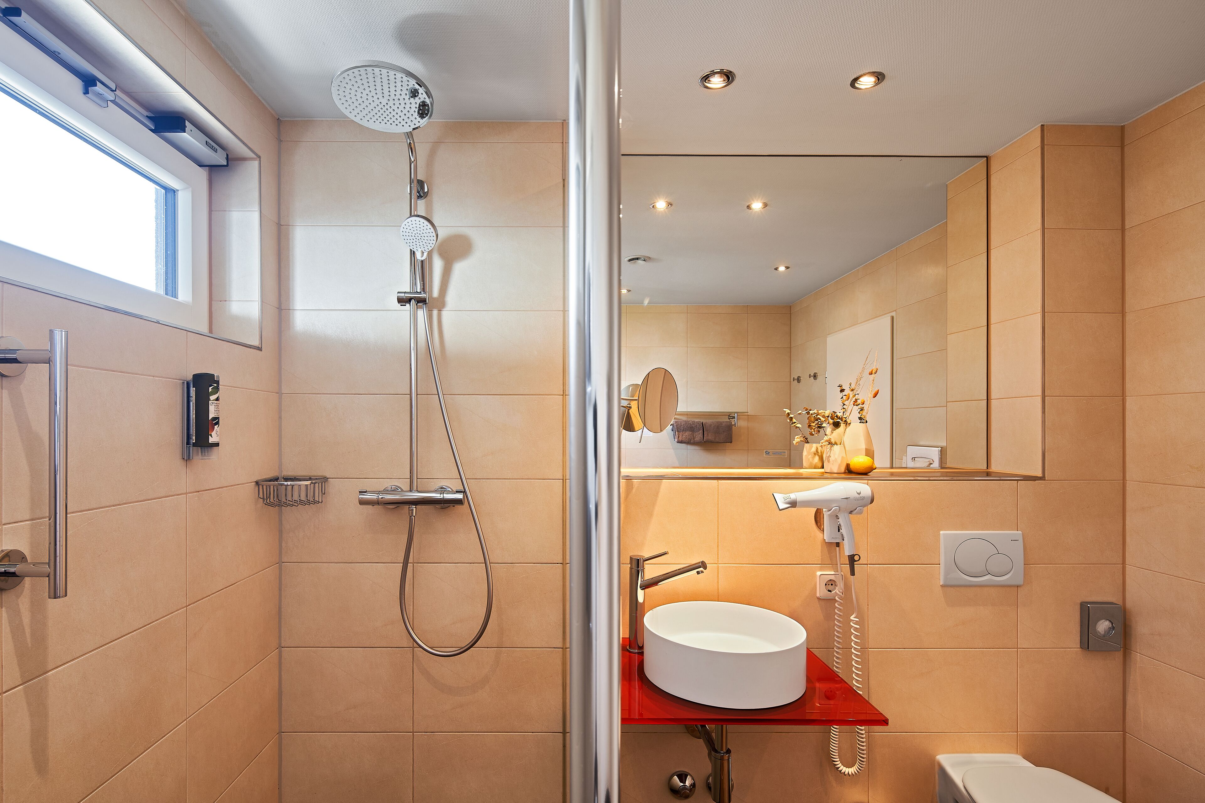 A modern bathroom with a glass-enclosed shower, a white sink, and a red countertop.