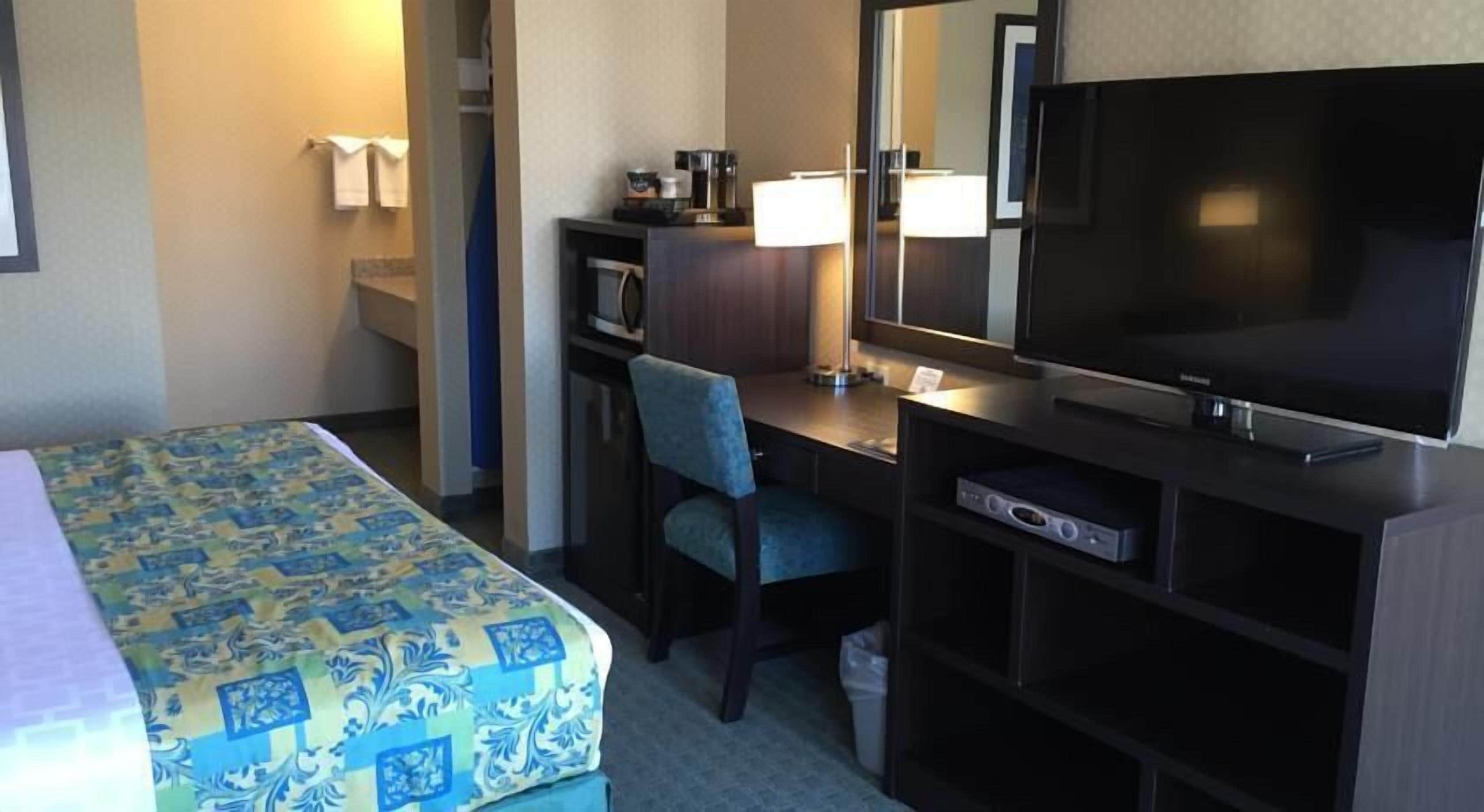 A hotel room with a bed, a desk, a television, and a small cabinet.