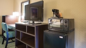 A hotel room with a desk, chair, television, and a refrigerator with a coffee maker. - Regency Inn SFO Airport (San Bruno)