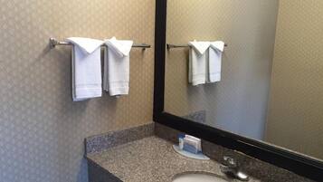 A bathroom with a granite countertop, a sink, and a mirror. There are two white towels hanging on a towel rack.