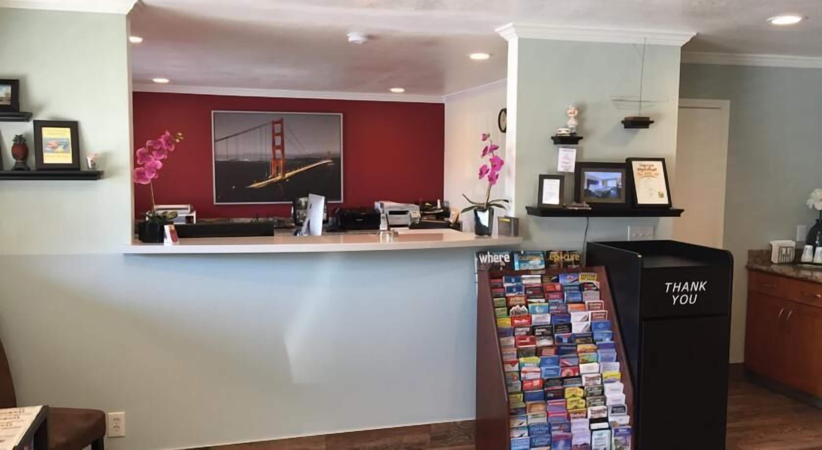 A reception area with a desk, a 'Thank You' sign, a wall-mounted display of brochures, and a framed picture of the Golden Gate Bridge.