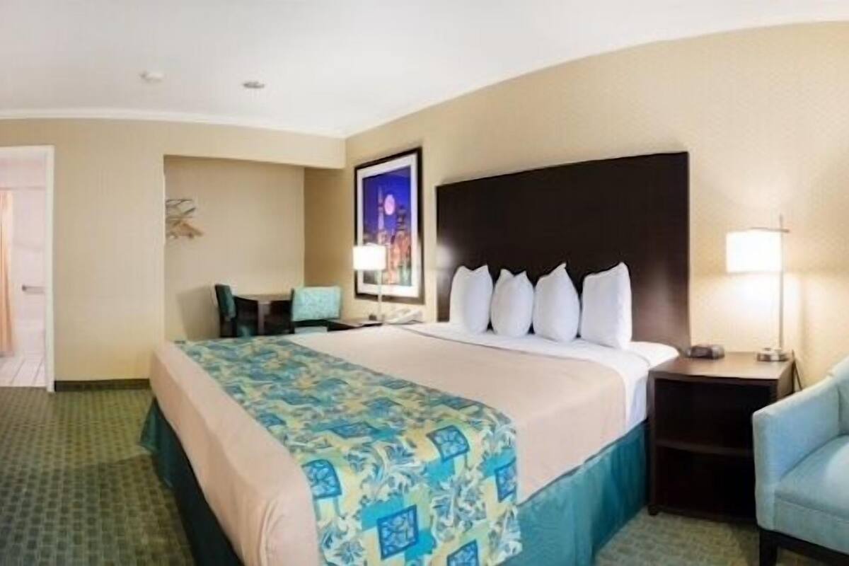Una habitación de hotel con una cama grande, un escritorio, una silla y un televisor.
