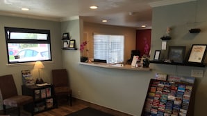 A reception area with a desk, chairs, a bulletin board with travel brochures, a window with blinds, and a door. - Regency Inn SFO Airport (San Bruno)