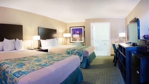 A hotel room with two beds, a desk, a chair, and a television. - Regency Inn SFO Airport (San Bruno)