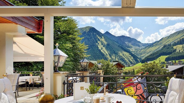 Terraza con mesa lista para comer, sillas y vistas a montañas.