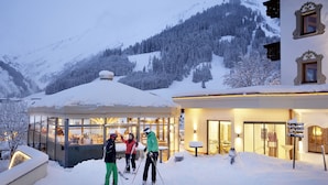 Una montaña cubierta de nieve con un edificio que tiene ventanas grandes y un recinto de cristal.