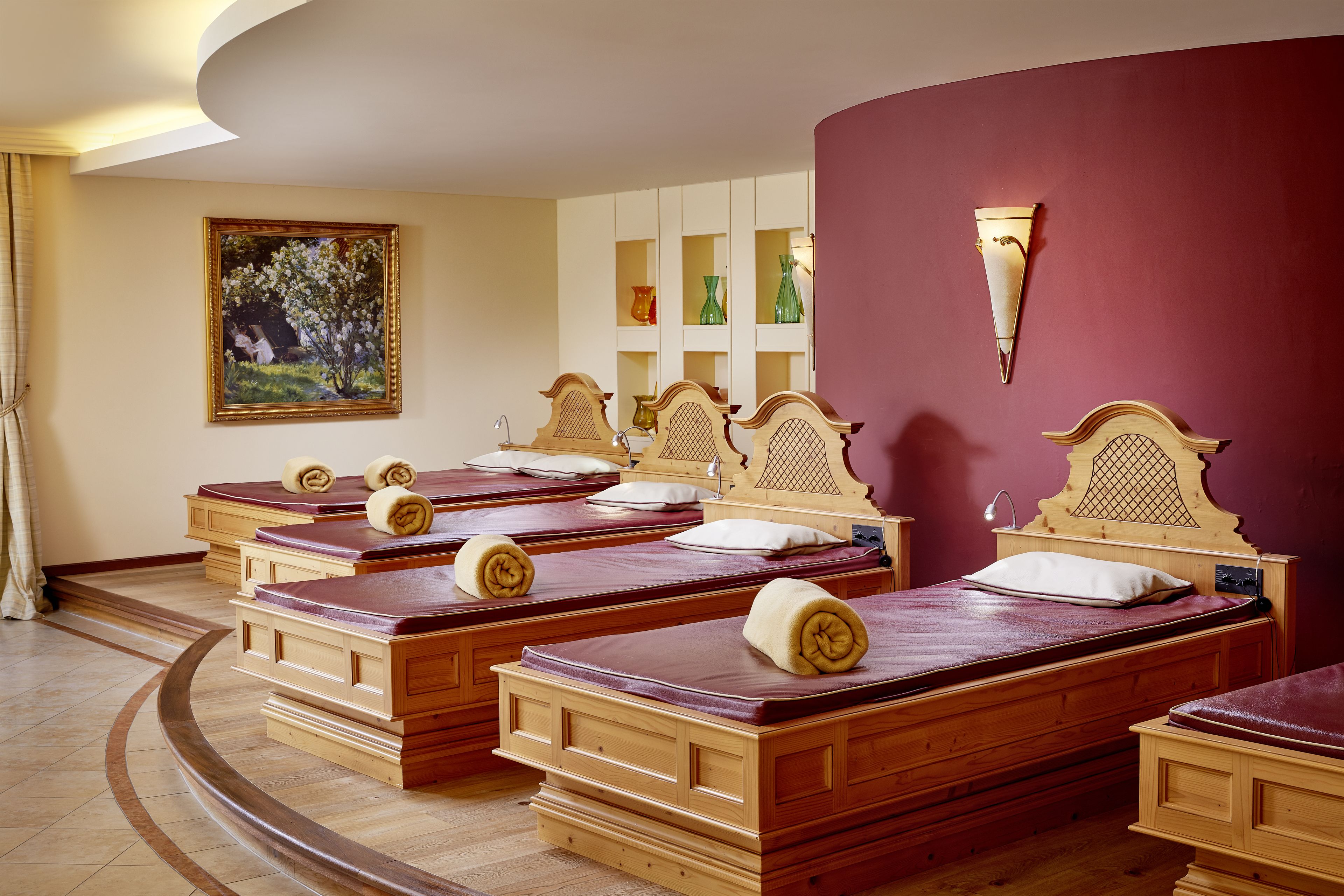 Ein Hotelzimmer mit mehreren Holzbett, einem Bild an der Wand und einer roten Akzentwand.
