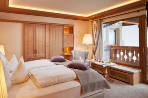 Habitación de hotel con una cama grande, un escritorio con lámpara, una silla y una ventana con cortinas.