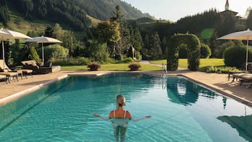 Alberca techada, alberca al aire libre y sombrillas en la alberca