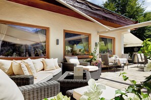 An outdoor seating area with wicker furniture, a laptop on a table, and a view of the surrounding landscape. - Hotel Singer - Relais & Châteaux (Berwang)
