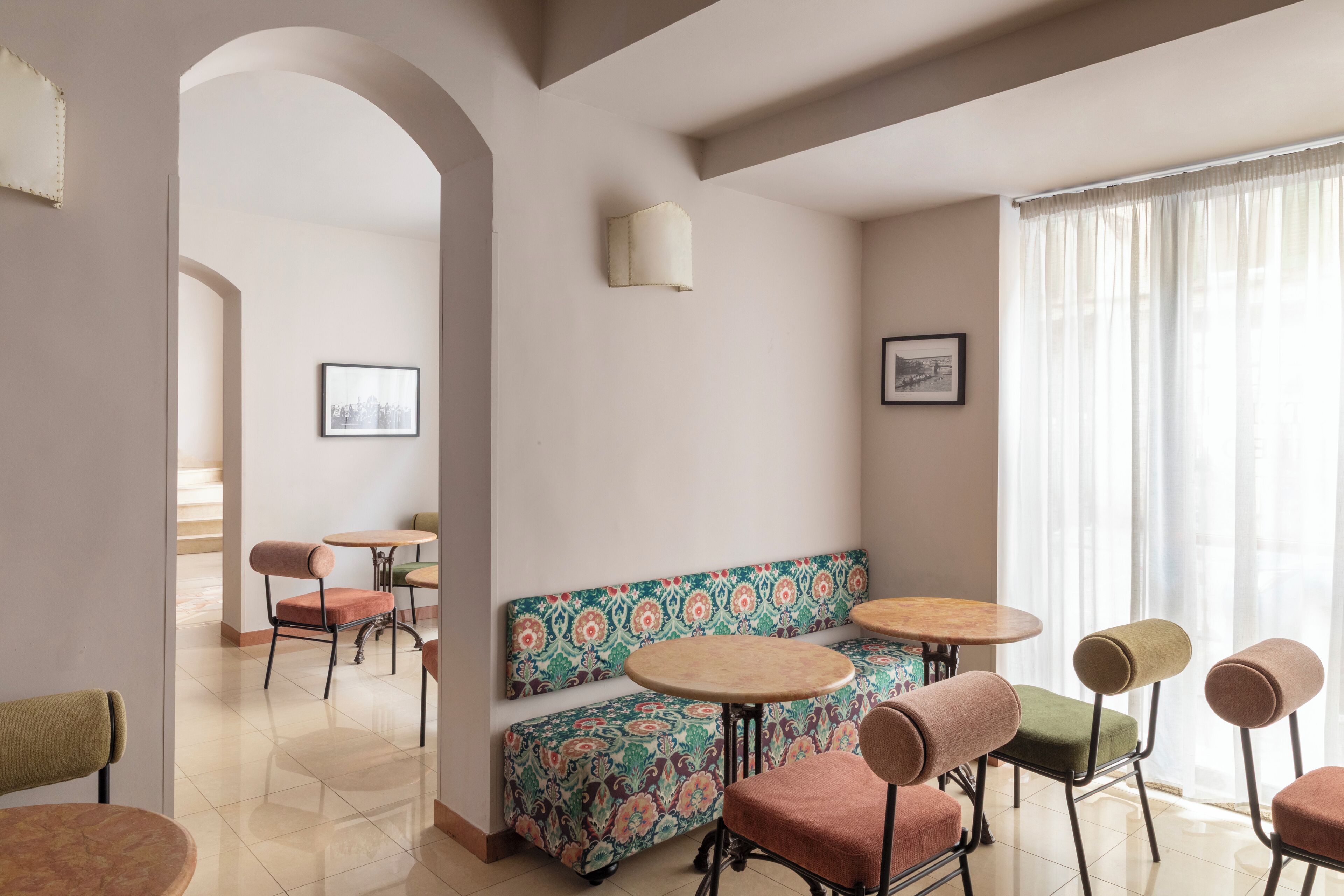 A dining area with round tables, cushioned chairs, and a patterned bench.