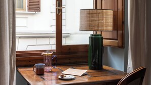 Un escritorio de madera con una lámpara, una taza y un cuaderno.