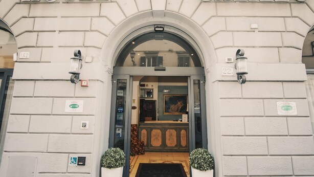 La entrada del Hotel Galileo, con un arco clásico, una recepción y vista del interior.