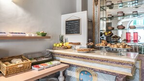 Un bufé de desayuno con diferentes opciones de comida, un menú en una pizarra y una exhibición de cerámica decorativa.