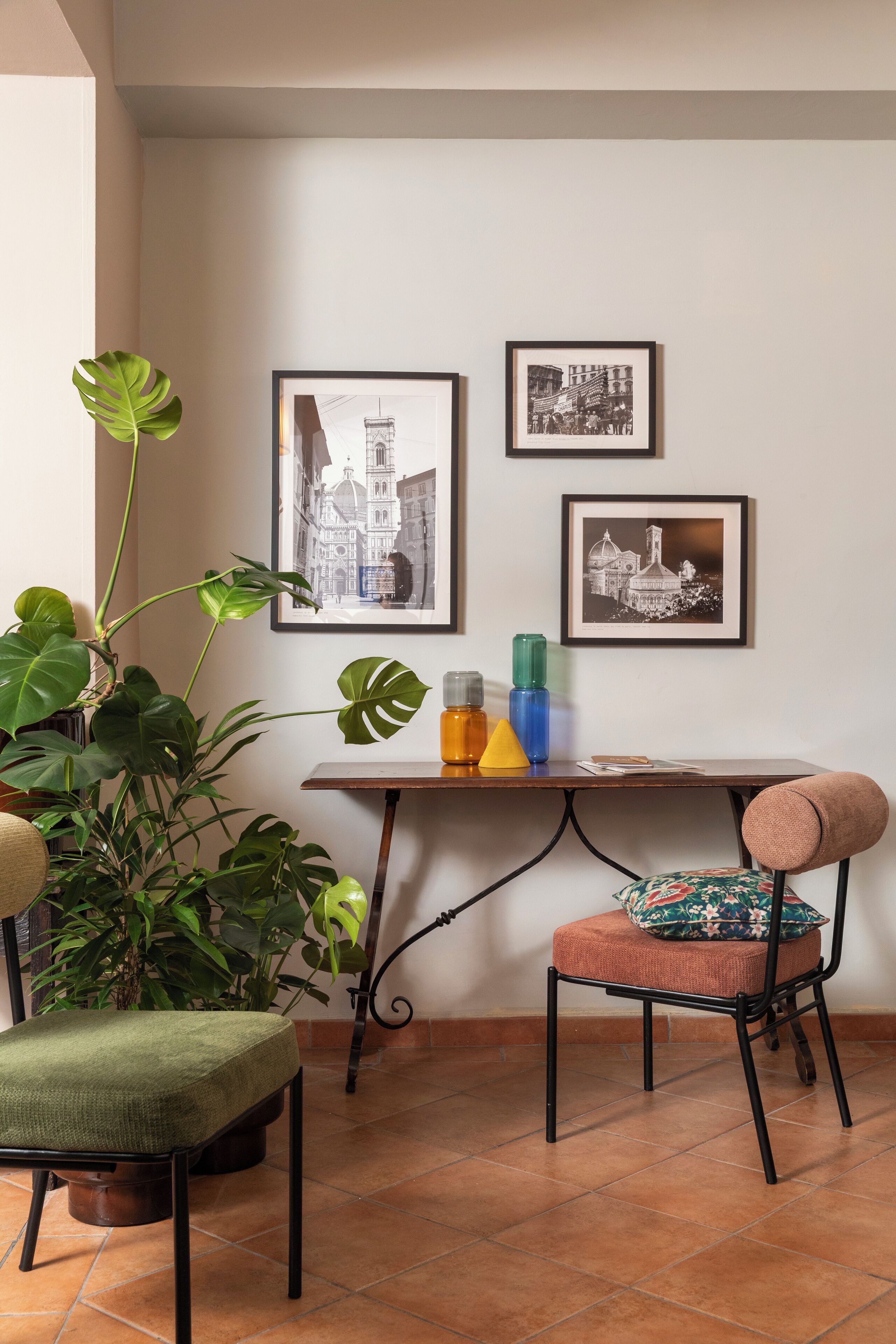 Habitación de esquina con una mesa, dos sillas, una planta en maceta y cuadros en la pared.