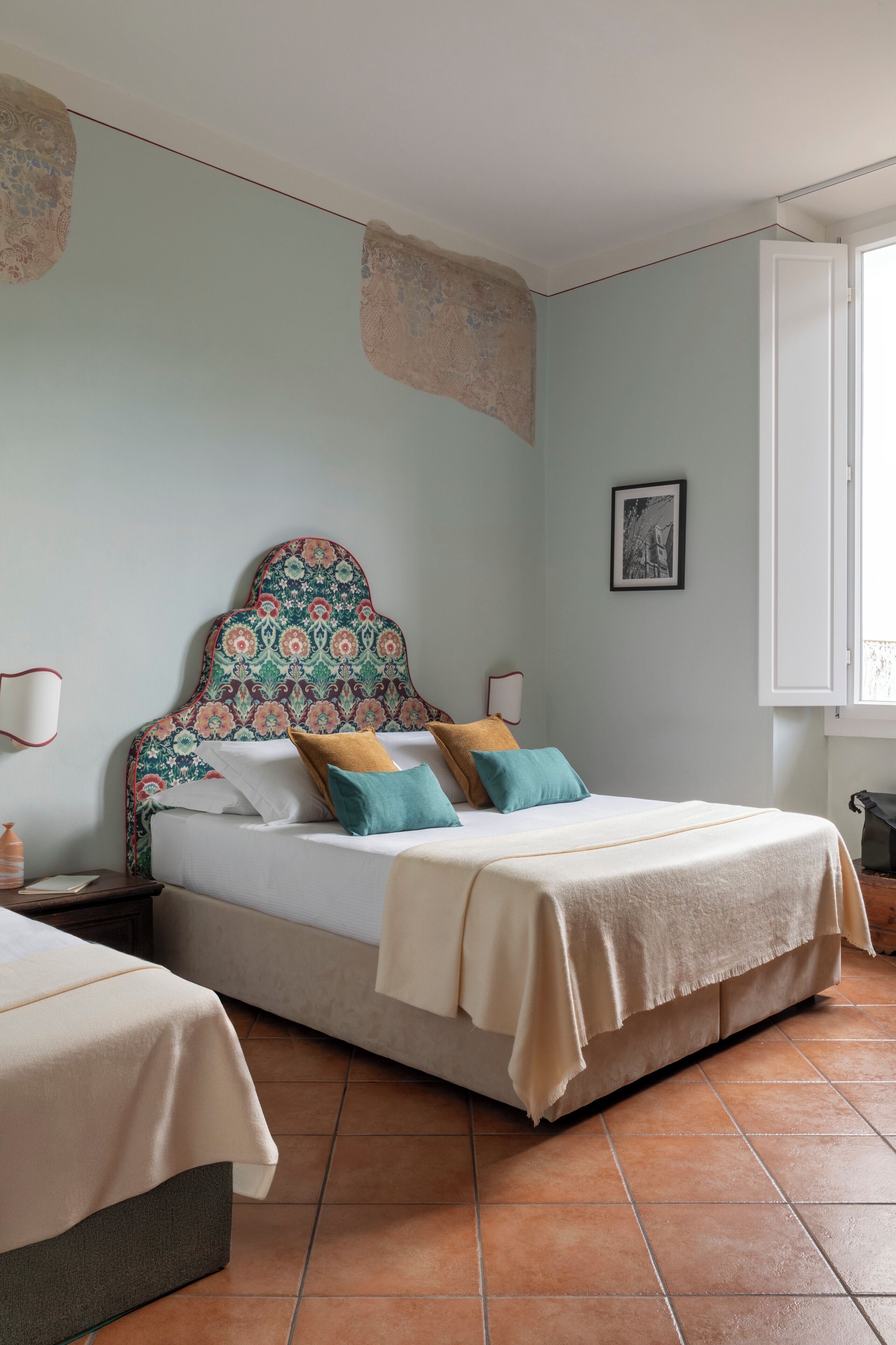 Une chambre à coucher avec un lit, une table de chevet, une lampe et une fenêtre.
