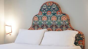 A bed with white linens and a headboard with a floral pattern.