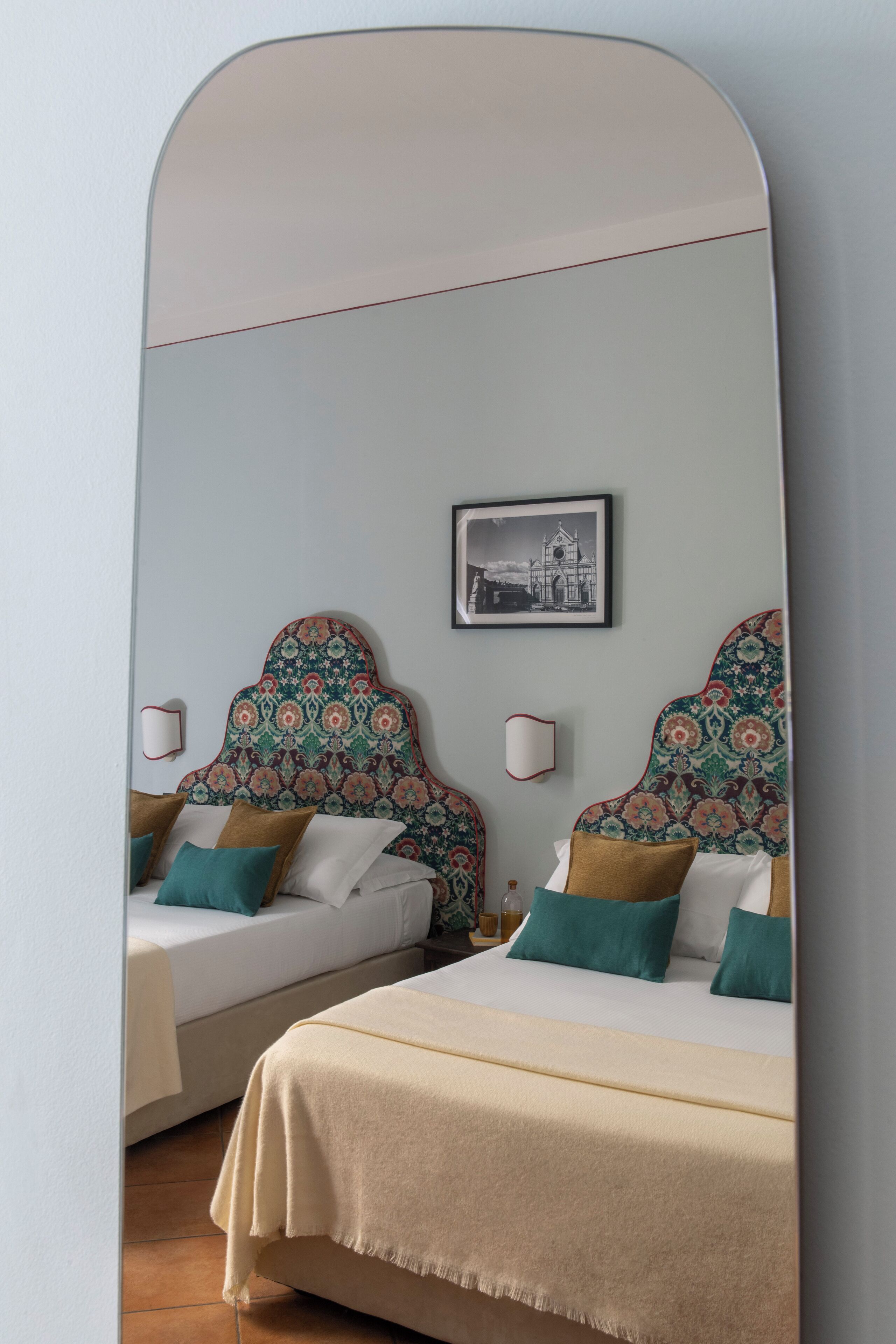 A bedroom with two beds, patterned headboards, a framed picture on the wall, and bedside lamps.